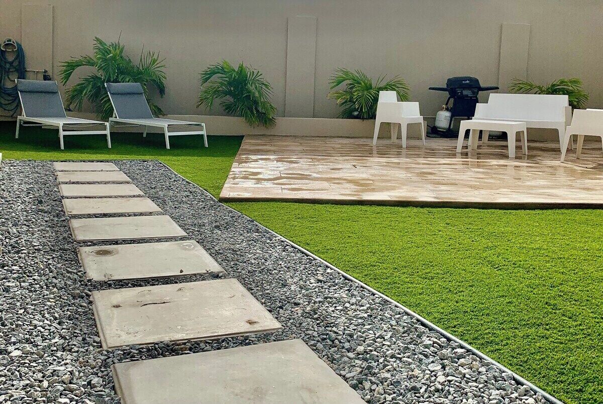 Een terras met buitenmeubilair, een pad en kunstgras.