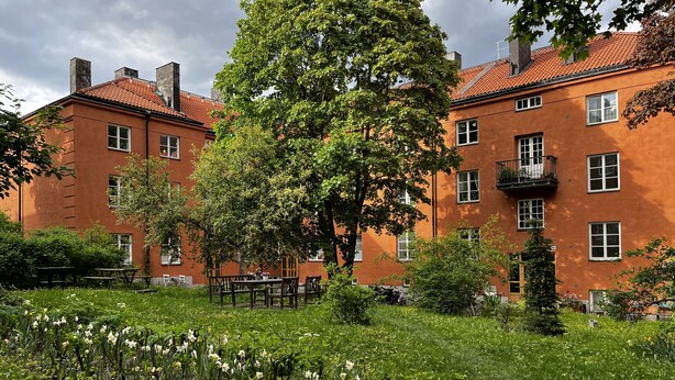 A building with multiple windows and balconies, surrounded by a garden with various plants and flowers. - Lovely Apartment in Stockholm City (Stockholm)