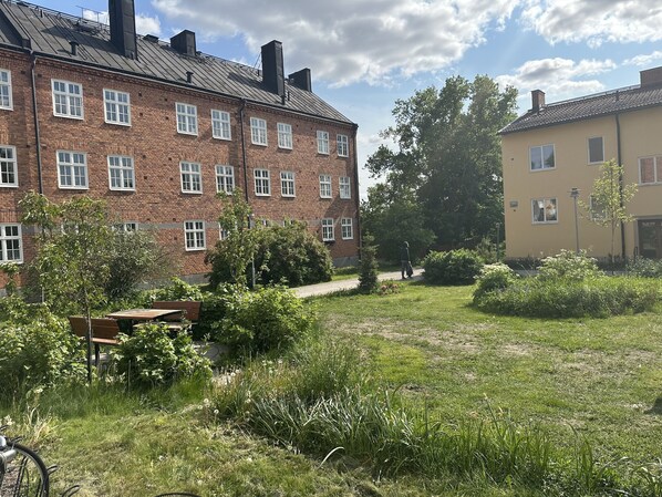 A courtyard with a brick building, a wooden bench, and a pathway. - Lovely Apartment in Stockholm City (Stockholm)