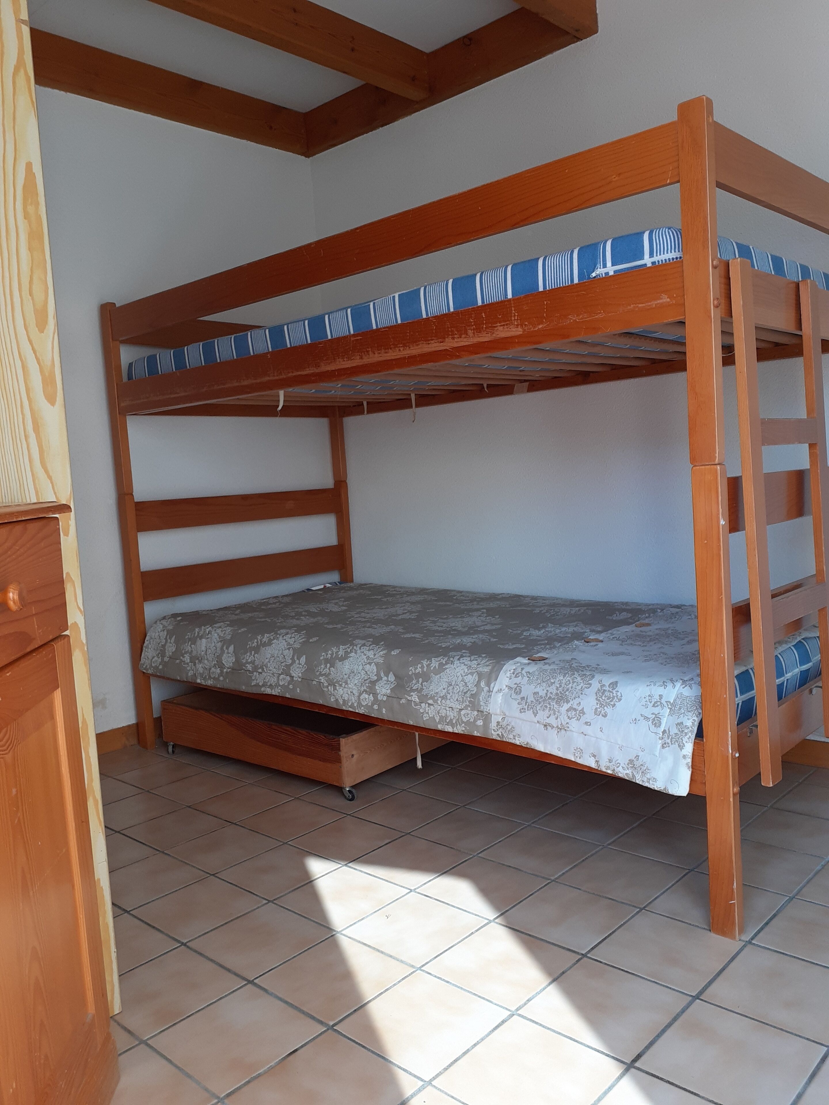 A bunk bed with a wooden frame and a mattress with a floral pattern.