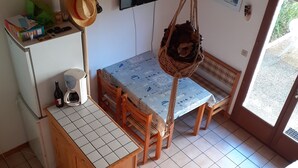 Una cocina compacta con suelo de baldosas, un refrigerador pequeño, una cafetera y un banco.