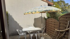 Un patio con una mesa y sillas, un parasol decorativo y un portón de madera.