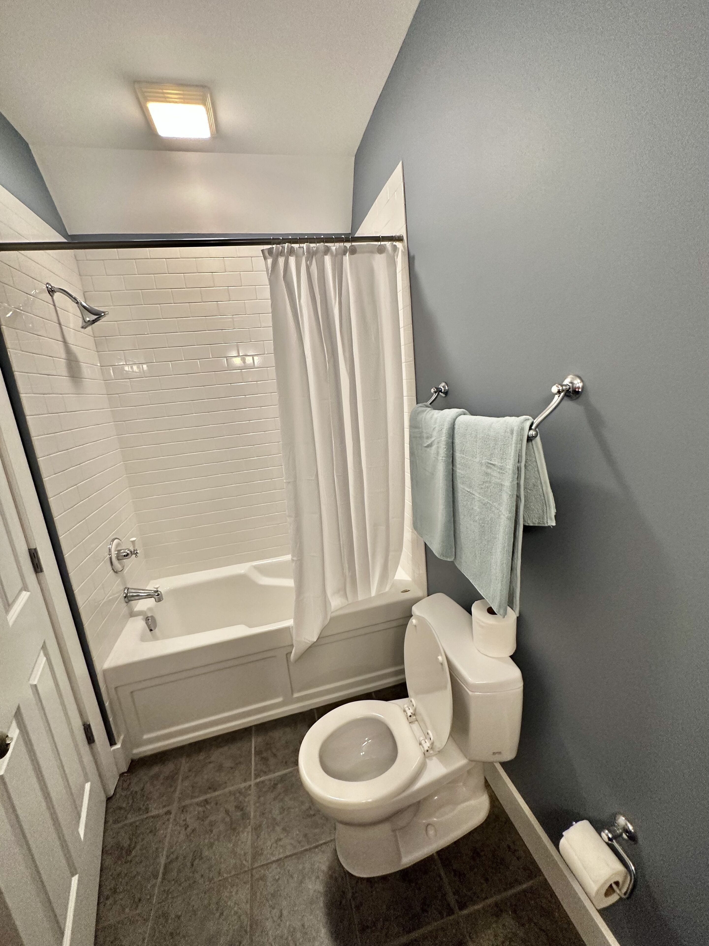 A bathroom with a bathtub, toilet, and shower curtain.