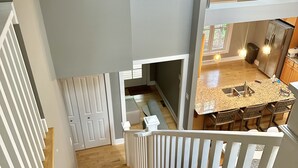 A staircase with white railings leading to a kitchen area with a dining table and chairs. - Modern Lakeshore Home! 2 minute drive to the beach! Community pool 3 houses away (Union Pier)