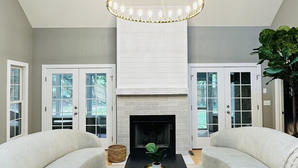 A modern living room with a black coffee table, two white sofas, a fireplace, and a chandelier. - Modern Lakeshore Home! 2 minute drive to the beach! Community pool 3 houses away (Union Pier)