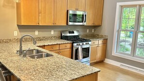 A kitchen with granite countertops, stainless steel appliances, wooden cabinets, and pendant lighting. - Modern Lakeshore Home! 2 minute drive to the beach! Community pool 3 houses away (Union Pier)