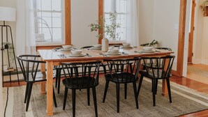 A dining area with a wooden table set for six, surrounded by black chairs. - Riverside Historic Home near Downtown, Wineries, Hiking (Taylors Falls)