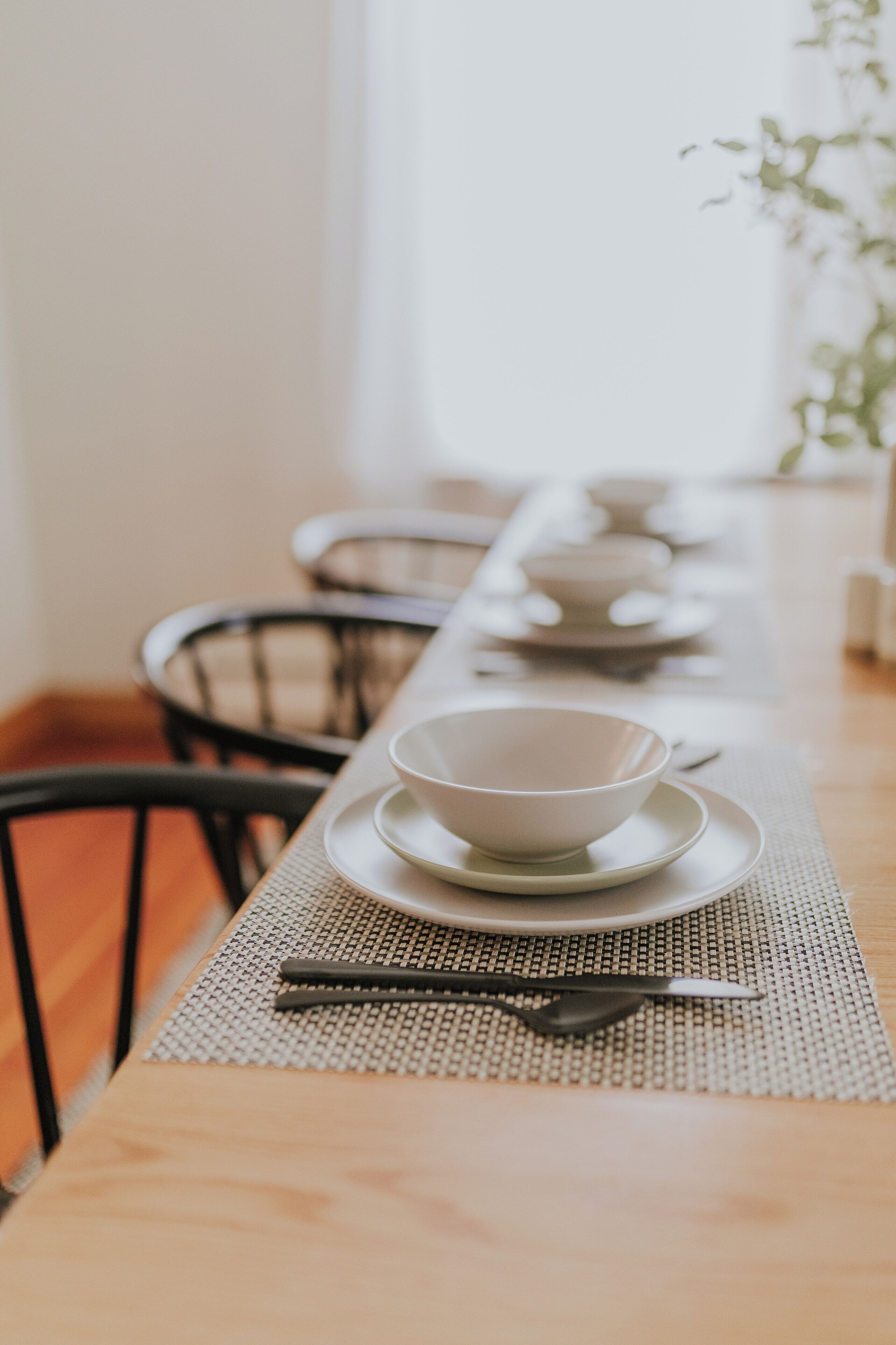 Une table à manger avec un set de table, un bol, une cuillère et des baguettes.