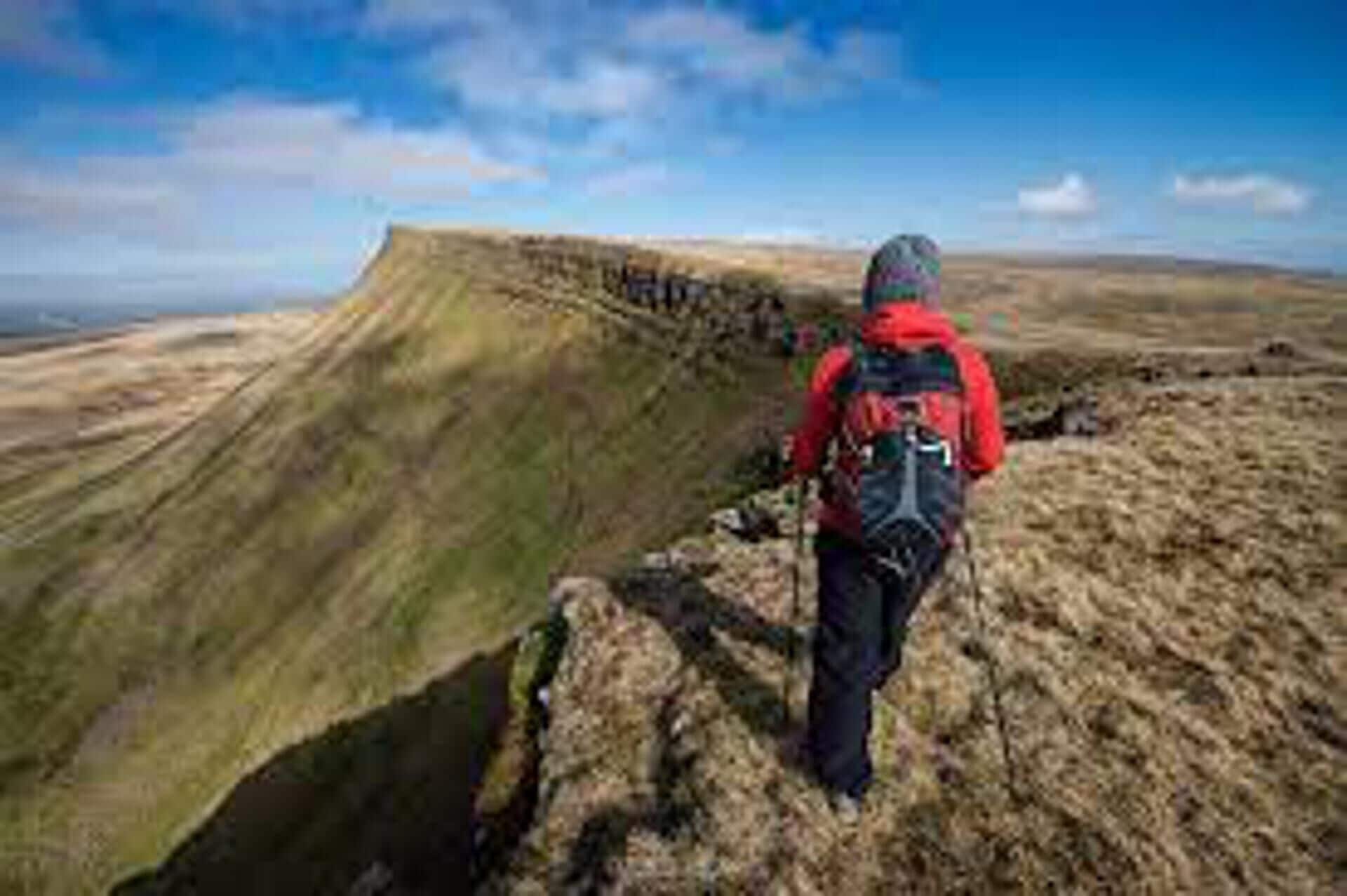 A hiker with a backpack on a grassy hill.