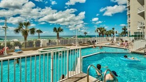 A swimming pool area with multiple pools, palm trees, and a view of the ocean. - Seaglitz - 2 bed 2 bath Oceanfront (Miramar Beach)