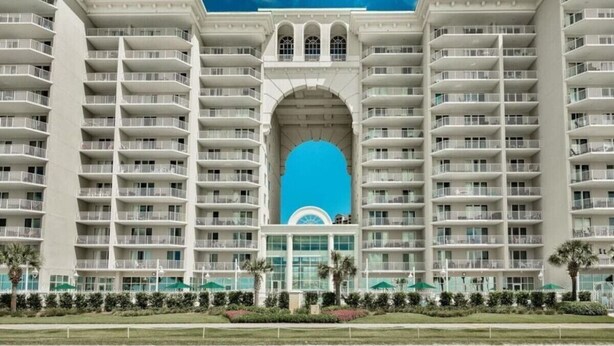A multi-story hotel with a central arched entrance and balconies on each floor. - Seaglitz - 2 bed 2 bath Oceanfront (Miramar Beach)