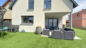 A modern two-story house with a covered patio area, a trampoline, and outdoor furniture. - Maison Spacieuse Avec Piscine , Idéale Pour les Familles (Hilsenheim)