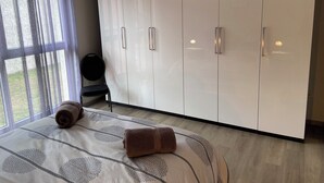 A bedroom with a large wardrobe, a bed with patterned bedding, and a chair. - Maison Spacieuse Avec Piscine , Idéale Pour les Familles (Hilsenheim)
