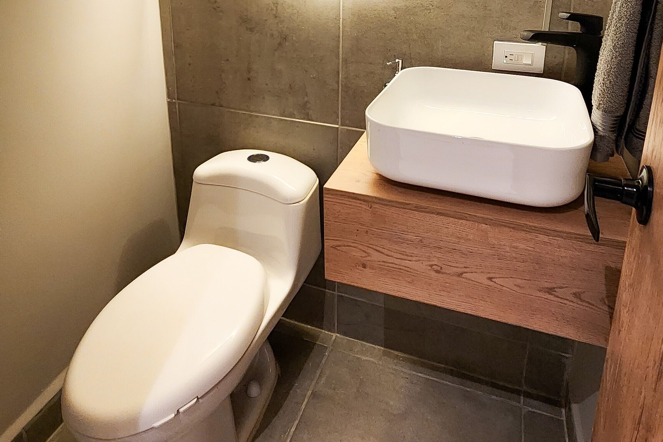 Un bagno con il water, un lavandino bianco e un mobile contenitore in legno.