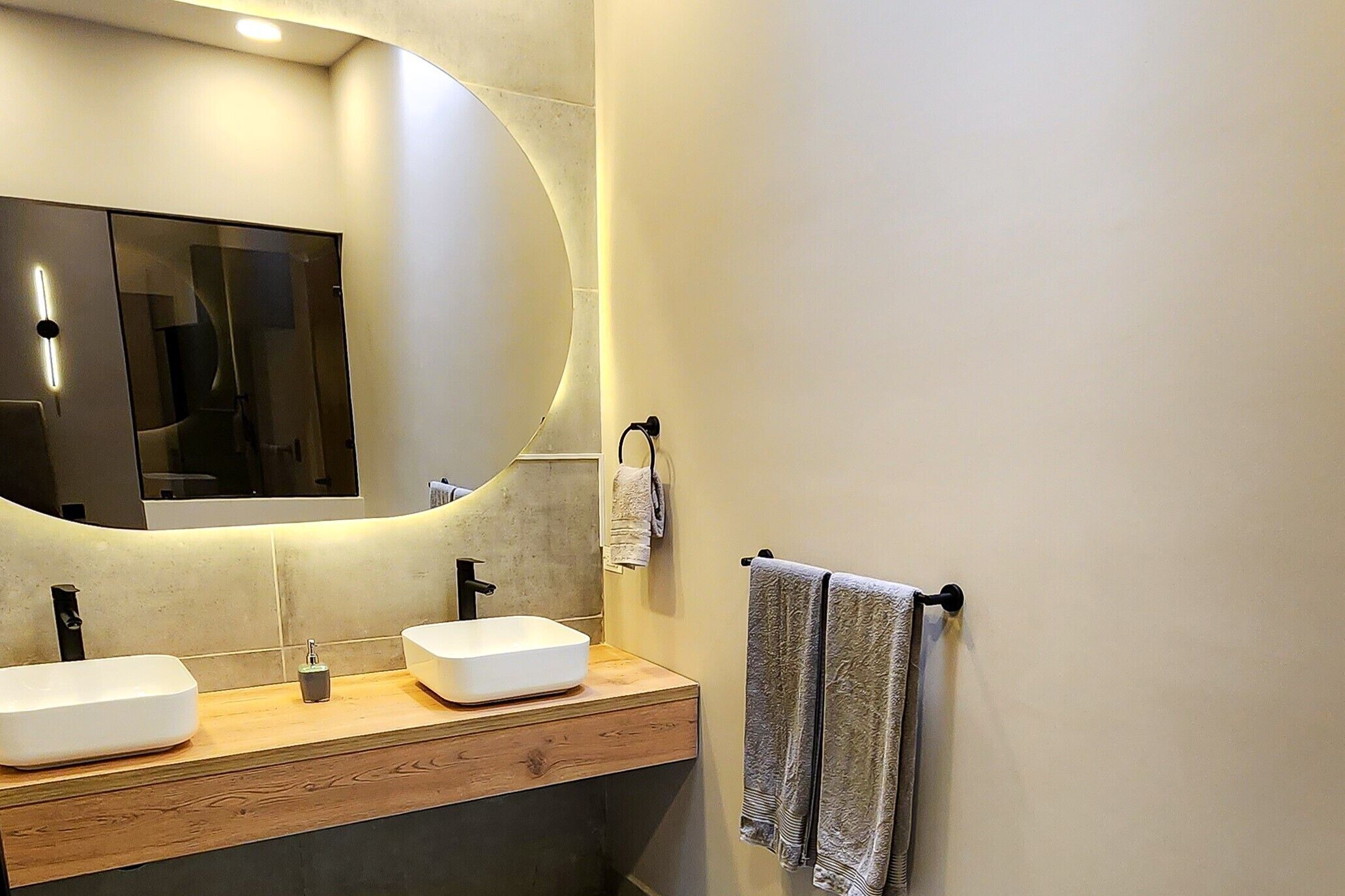 Ein modernes Badezimmer mit zwei Waschbecken, einem großen Spiegel und einem Handtuchhalter.