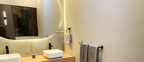 Ein modernes Badezimmer mit zwei Waschbecken, einem großen Spiegel und einem Handtuchhalter.