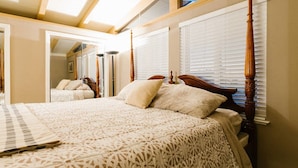 Ein Schlafzimmer mit einem großen Bett, einem hölzernen Kopfende und einem Dachfenster.