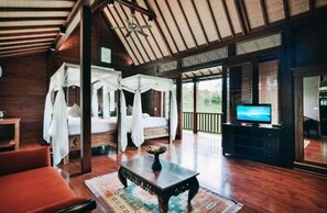 A spacious room with a large bed, a television, and a wooden coffee table.