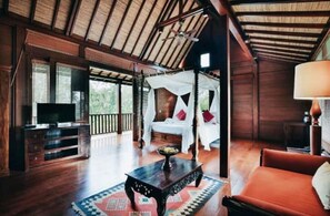 Relax in a spacious room with a high ceiling, comfortable seating area, and a TV, plus a window offering a view of the outdoors.
