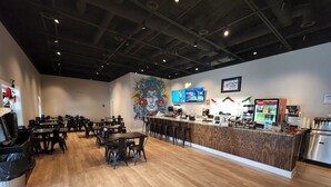A restaurant with a wooden floor, a counter with a menu, and a TV screen displaying content.