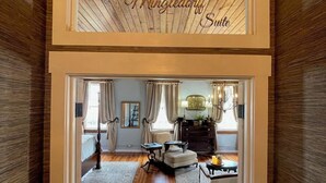 A hallway leading to a room with a wooden ceiling and a sign reading "The Winkledoff Suite".