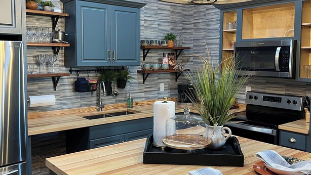 A modern kitchen with a central island, stainless steel appliances, and a chandelier.