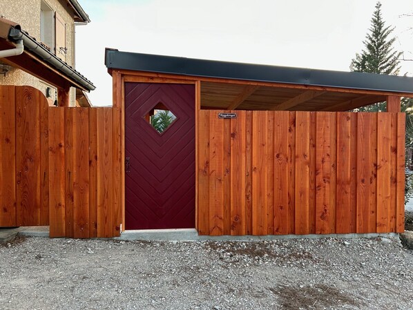A wooden gate with a red door, a metal roof, and a gravel driveway. - Big house next to Die city center, with view (Die)