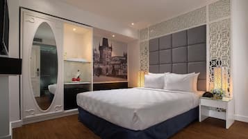 Une chambre d’hôtel avec un grand lit, une armoire avec un miroir, un panneau décoratif au mur et une table de chevet avec une lampe.