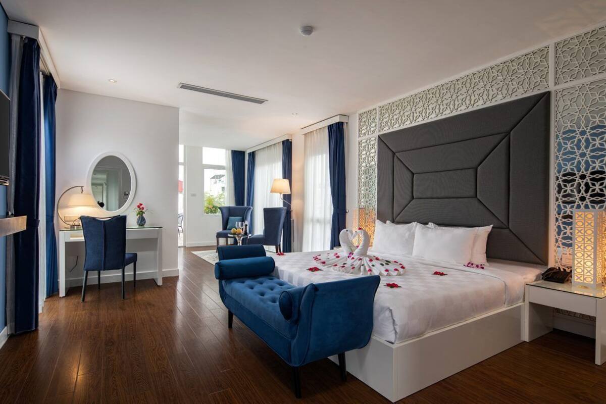 A modern hotel room with a large bed, a desk, and a chair.