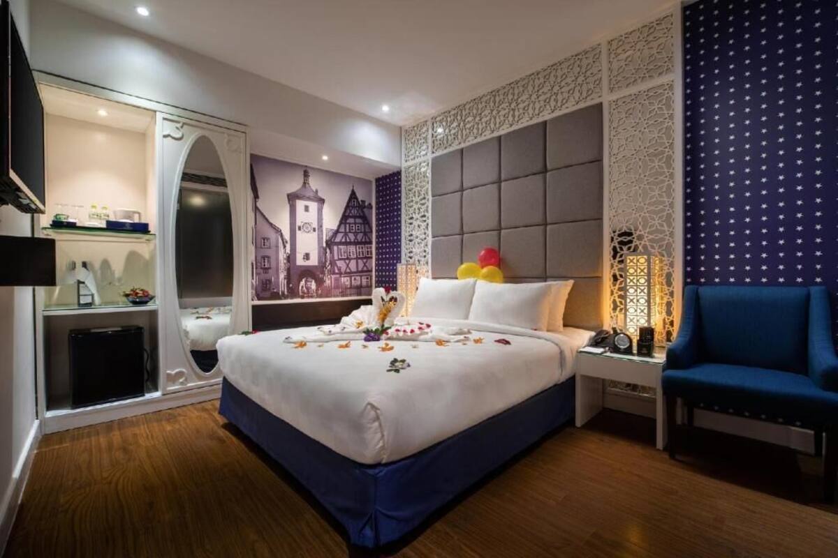 A hotel room with a bed, a nightstand, a chair, a wardrobe, and a wall mural.