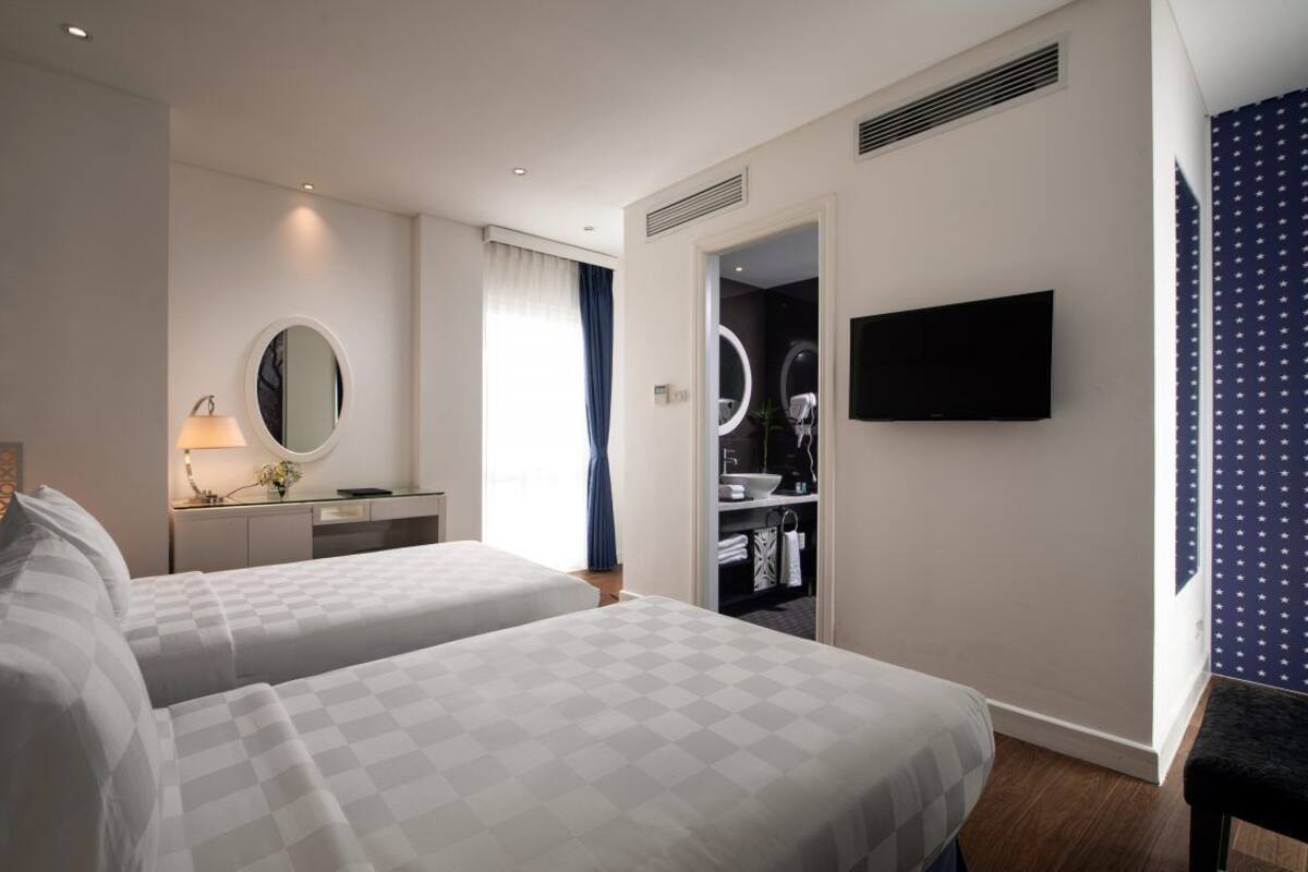 A hotel room with two beds, a TV, a mirror, a vanity, and a wardrobe.