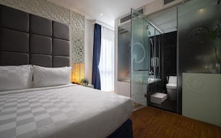 Een moderne hotelkamer met een groot bed, een douche met glazen wanden en een apart toilet.