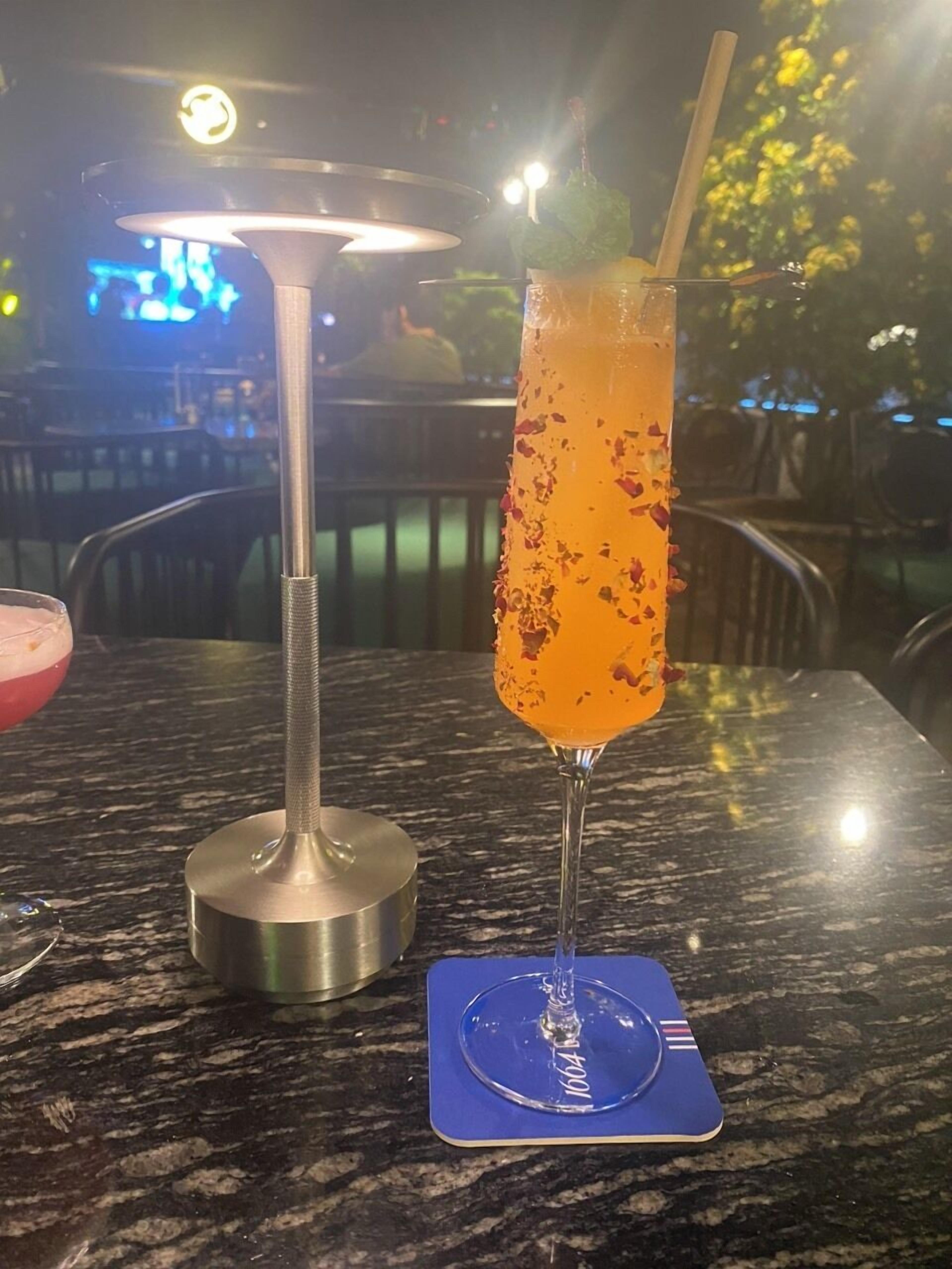 A cocktail on a table with a metal shaker and a blue coaster.