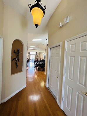 A hallway with wooden flooring, white doors, and a ceiling light fixture.