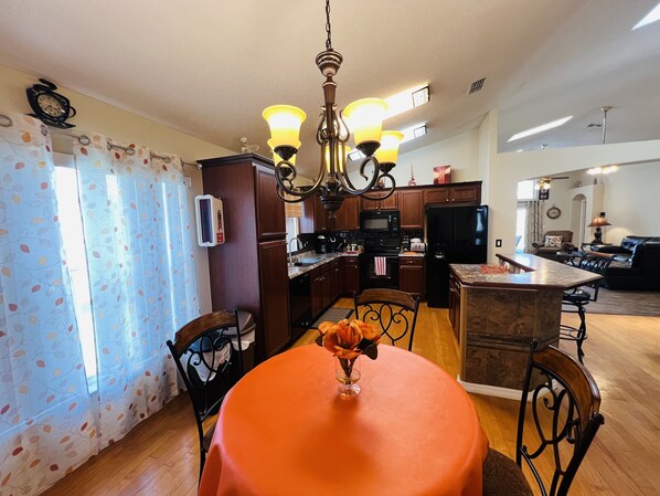 A modern kitchen with dark wood cabinets, a central island, and a dining area with a round table and chairs.