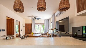 Una sala de estar moderna con una mesa redonda, un sofá, un televisor y lámparas colgantes de mimbre.
