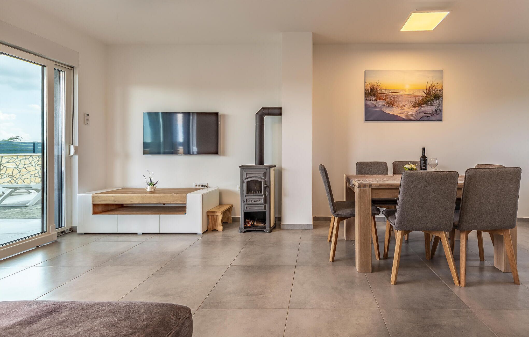 Un salon moderne avec une cheminée, un coin repas et une grande fenêtre.