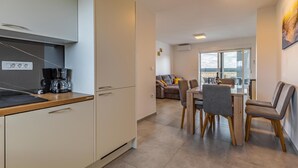 Una cocina moderna con cafetera, un comedor con mesa y sillas, y un balcón con vistas.