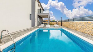 Piscina con pared de piedra y barandilla de metal en un lateral.