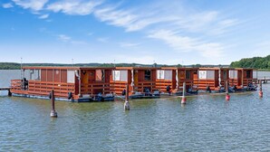 A row of wooden floating cabins with windows and doors, docked on a calm lake. - 2 bedroom amazing ship in Beetzsee (Beetzsee)