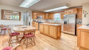 A spacious kitchen with wooden cabinets, a central island, and stainless steel appliances. - Family-sized Cozy Cottage - mountains views, fishing, & hot tub, in Suches, GA (Suches)