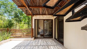 Eine moderne Terrassenanlage im Freien mit einer Holz-Pergola, einer Steinmauer und einer Glastür, die zu einem Schlafzimmer führt.