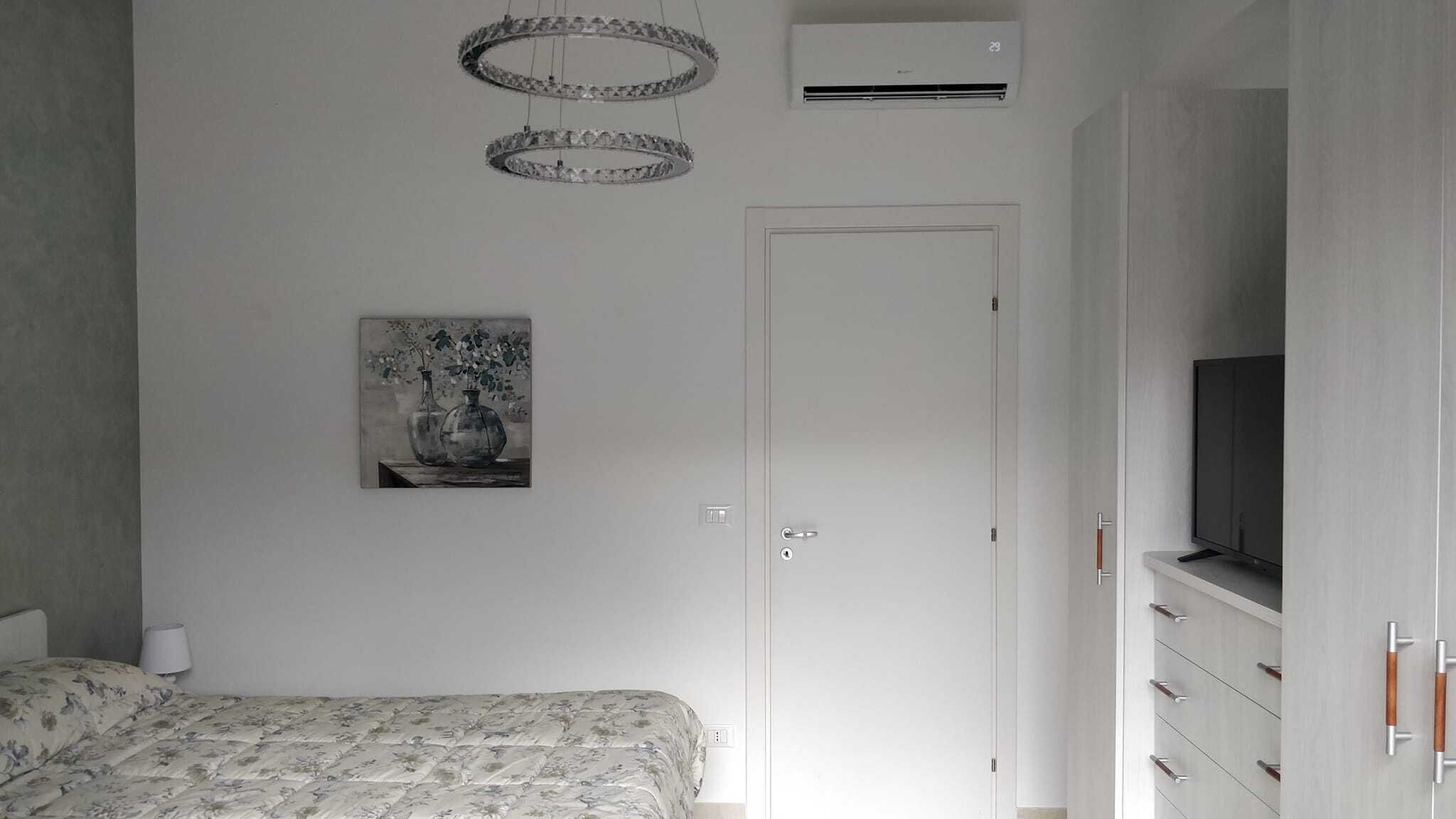 Een slaapkamer met een bed, een schilderij, een kledingkast en een televisie.