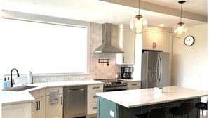 A modern kitchen with a large island, stainless steel appliances, and pendant lighting. - 4BD 4.5BA Pet-Friendly Riverfront Home (Saco)