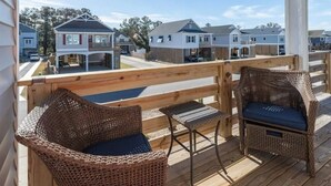 A wooden deck with wicker furniture and a view of residential buildings.