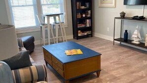 A living room with a sofa, a coffee table, a bookshelf, a ladder, and a TV on a stand.