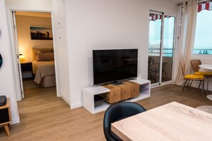 Una sala de estar moderna con un televisor de pantalla plana, un mueble de madera y un comedor con mesa y sillas.