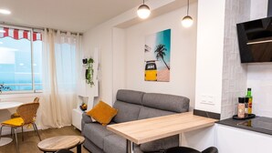 Un espacio habitable compacto con sofá, una pequeña mesa de comedor y una zona de cocina.