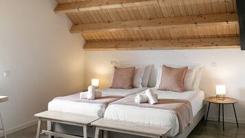 Une chambre avec un plafond en bois incliné, un lit avec deux oreillers, une table de chevet, un luminaire suspendu et un tapis.