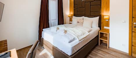 A hotel room with a large bed, wooden headboard, and a wooden floor.